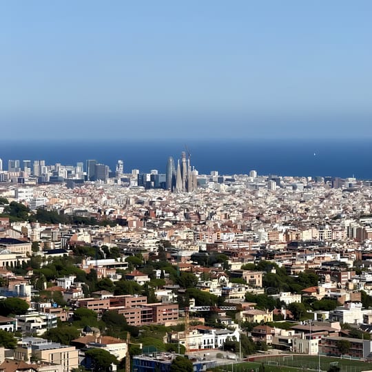 A misty autumn morning in Horta, Barcelona, with trees showing early signs of seasonal change and cool air settling over the city.