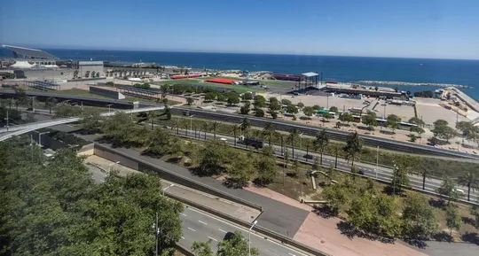 Aerial view of the Fòrum marine platform in Barcelona, showing a large, open concrete area next to the sea.