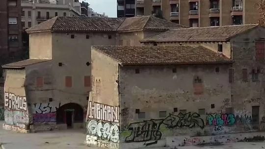 The neglected medieval Torre del Fang building in Barcelona, showing signs of disrepair and overgrowth.