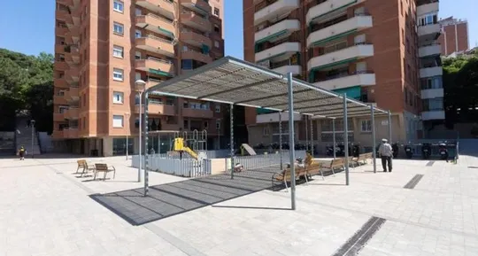 Newly renovated street in Barcelona's Can Baró neighbourhood with wide pavements and new paving, showing improved pedestrian 