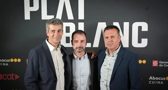 Three chefs, Oriol Castro, Eduard Xatruch, and Mateu Casañas, standing proudly in a professional kitchen, possibly at Disfrut
