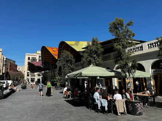 A busy street in Barcelona's Eixample district lined with cafes and restaurants, reflecting the city's diverse hospitality sc