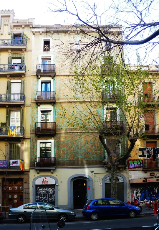 A renovated apartment building on Carrer de la Diputació in Barcelona's Eixample district, with balconies and street-level shops.