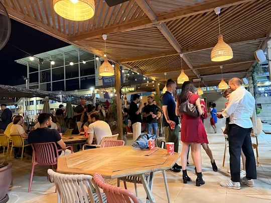 People chatting with drinks under wicker lamps on the Lemon Tree terrace at a Barcelona English Speakers meetup at night