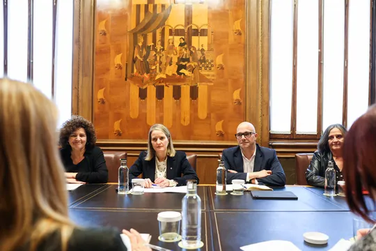 A family sitting together in a living room, symbolising foster care support in Catalonia.