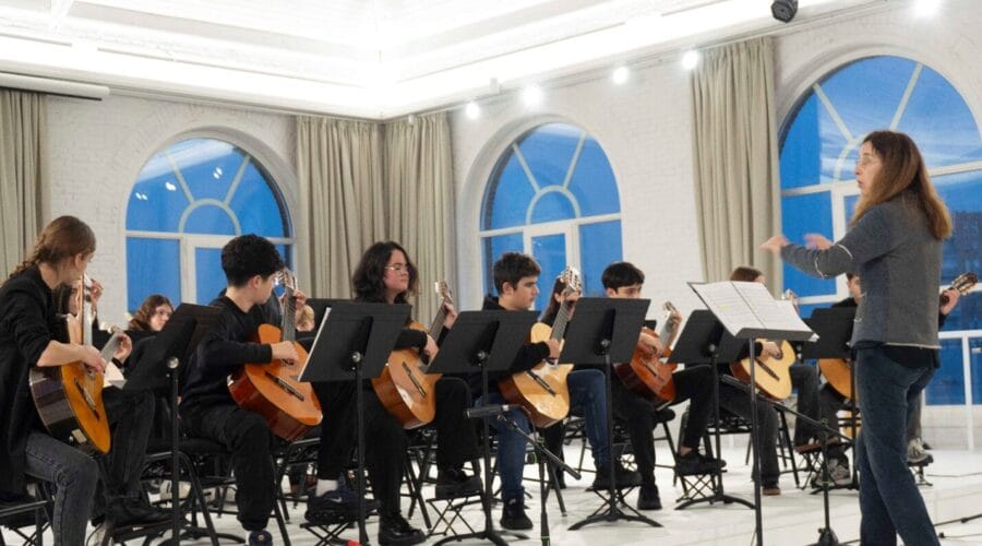 Students playing musical instruments in a bright classroom at a Barcelona municipal music school.