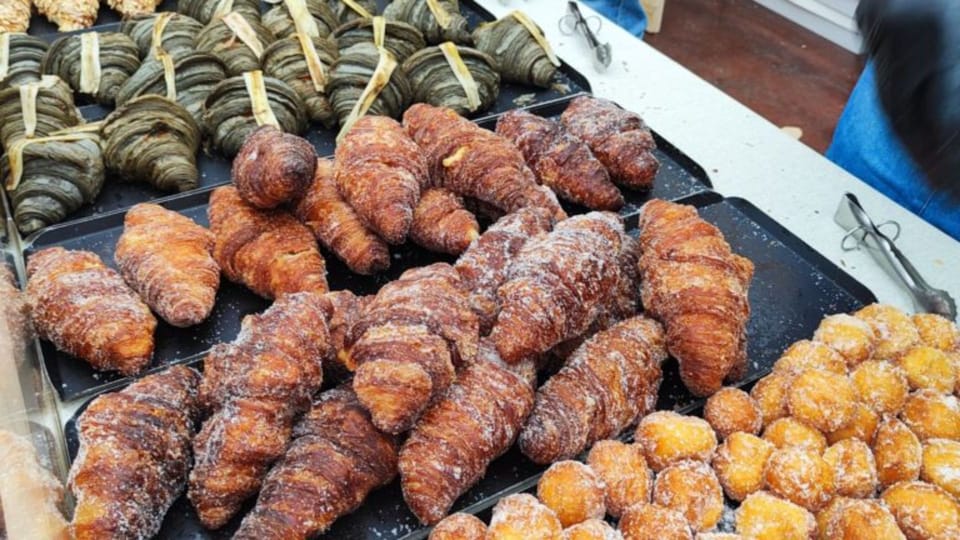 A variety of gourmet croissants, some sweet with fruit and cream, others savoury with cheese and meat, displayed on a table.