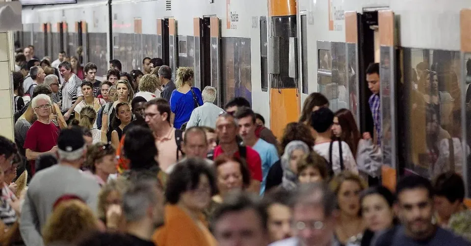 A Rodalies train arriving at a station platform in Barcelona, with commuters waiting.