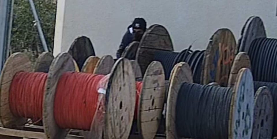 Police officers in uniform inspecting a pile of scrap metal, possibly copper or aluminium, at an industrial site.