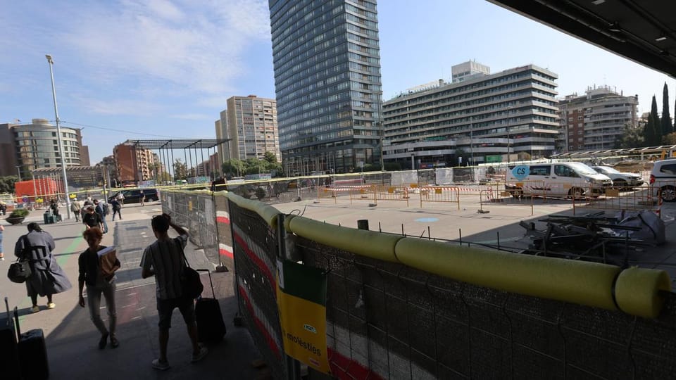 Exterior view of Sants bus station in Barcelona with buses parked at bays and people walking nearby.