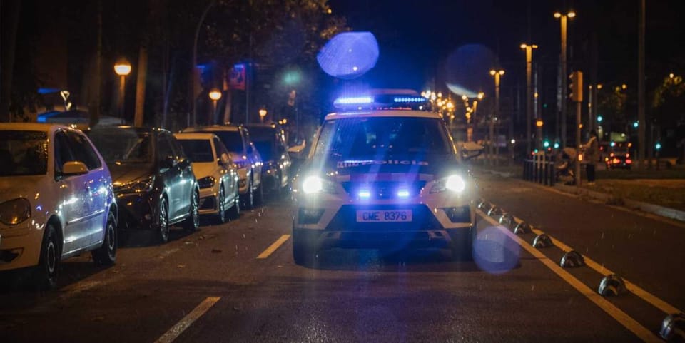 Police car with flashing lights on a street in Barcelona at night, representing increased patrols and crime response.
