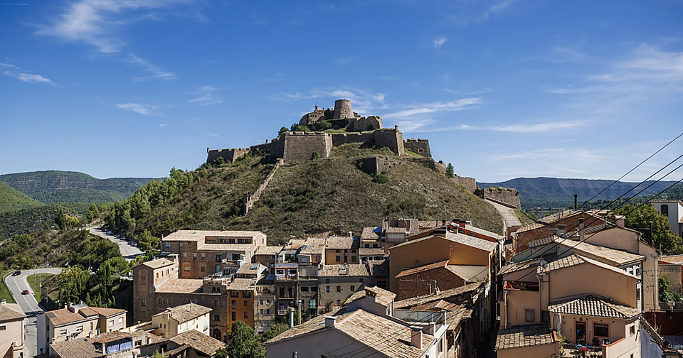Historic Cardona Castle, a medieval fortress with a tall tower and stone walls, under a clear sky.