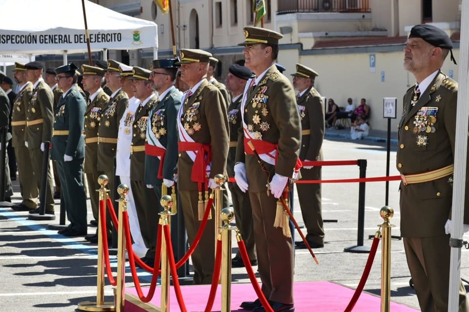 Civilians in a military courtyard raise their right hands to swear allegiance to the Spanish flag, held by soldiers.