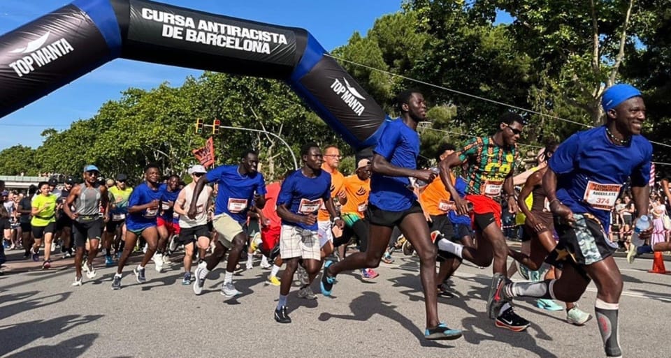 Runners participating in the Top Manta anti-racism race near the Magic Fountain of Montjuïc in Barcelona.