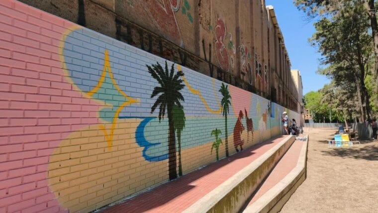 A colourful, abstract participatory mural on a wall in Barceloneta Park, showing various shapes and bright hues.