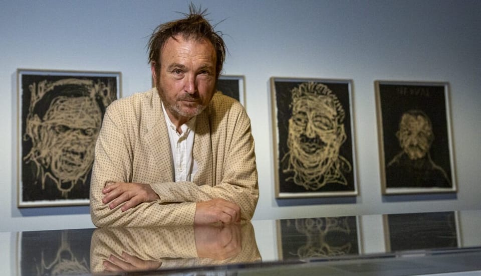 Miquel Barceló standing next to one of his large, textured engravings featuring marine elements, possibly an octopus, in an a