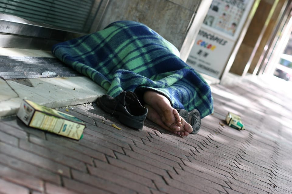 A person resting in shade on a Barcelona street during hot weather.