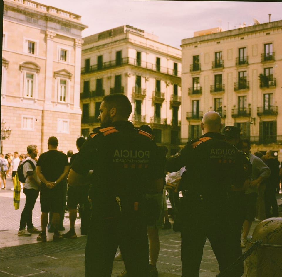 Mossos d'Esquadra officers patrol a busy public area in Catalonia during the summer safety operation.