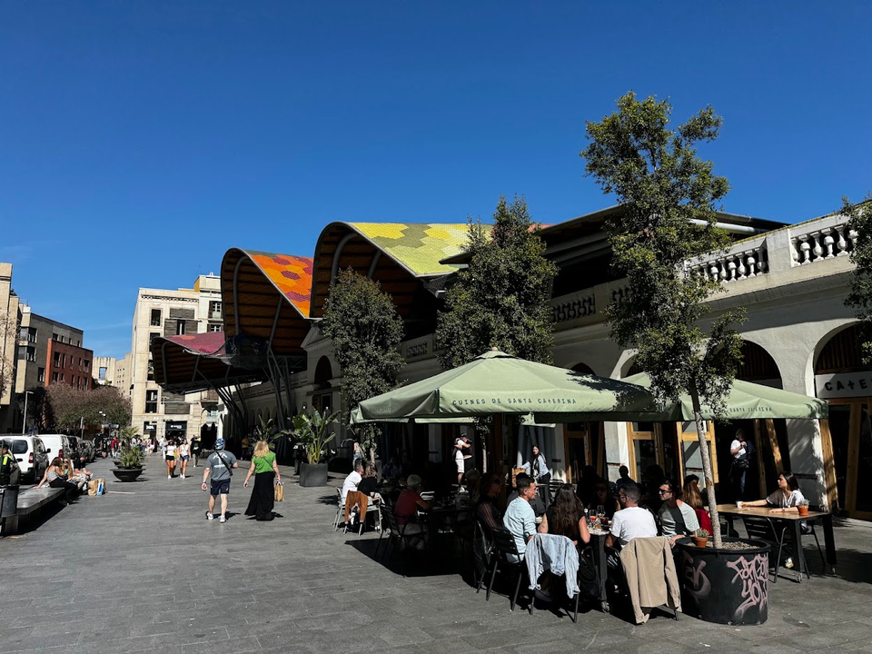 A busy street in Barcelona's Eixample district lined with cafes and restaurants, reflecting the city's diverse hospitality sc