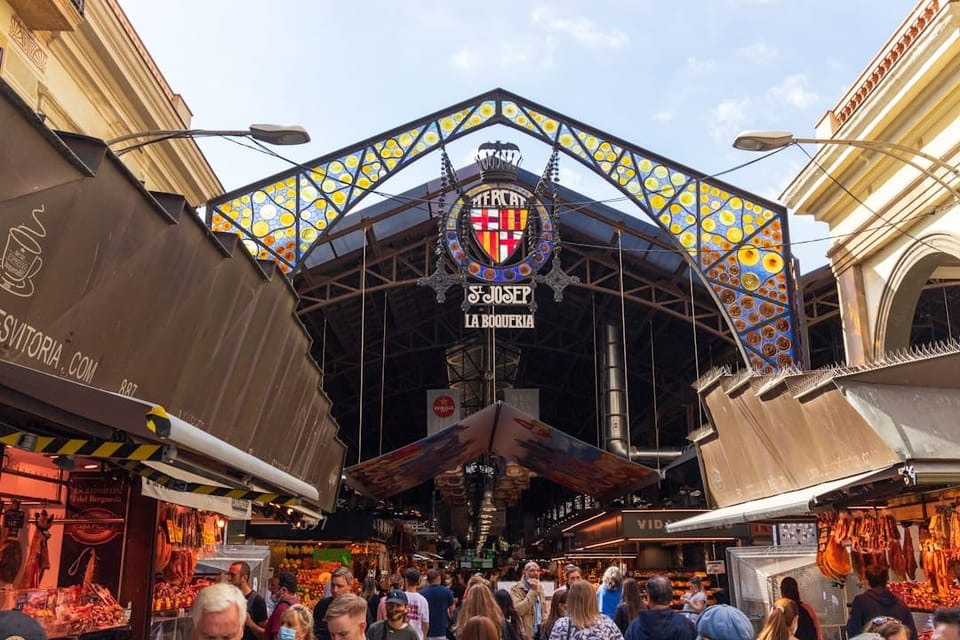 A bustling view inside Mercat de la Boqueria in Barcelona, showing packed stalls with fresh produce, seafood, and visitors un