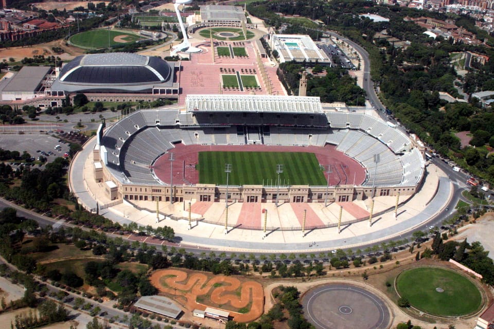 Aerial view of the Anella Olímpica in Barcelona, showing the Estadi Olímpic Lluís Companys, Palau Sant Jordi and surrounding areas under evening lights.