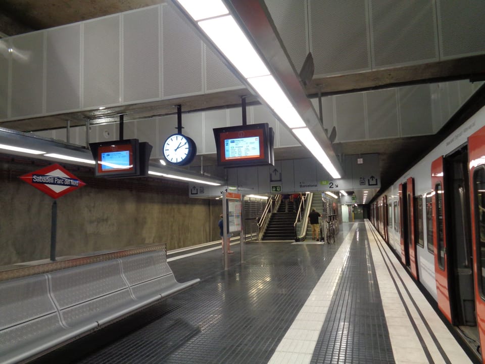 Night-time view of an FGC S2 train arriving at Sabadell Parc del Nord station during a public festival, with illuminated platforms and passengers boarding.
