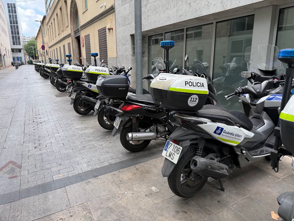 Guardia Urbana motorcycles parked beside Barcelona's seafront.