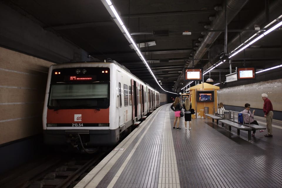 Queue of commuters waiting at a temporary bus stop outside FGC Gràcia station during line closure works in Barcelona.
