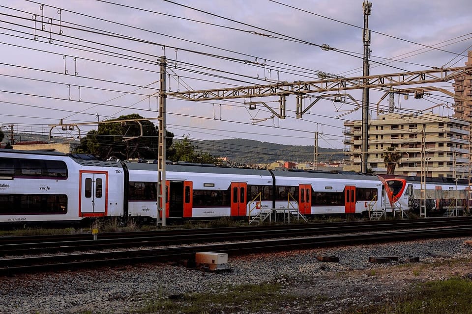 A Rodalies R1 train at Mataró Station, with passengers boarding under the platform canopy.
