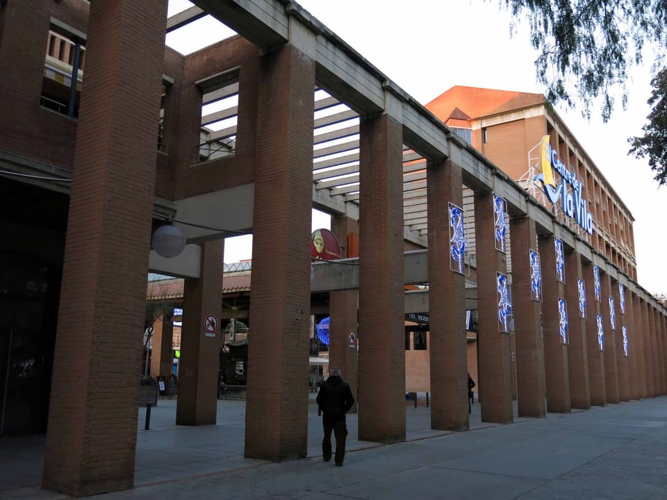 Interior of the neglected Centre de la Vila shopping centre in Barcelona's Vila Olímpica, showing empty storefronts and signs of disrepair.