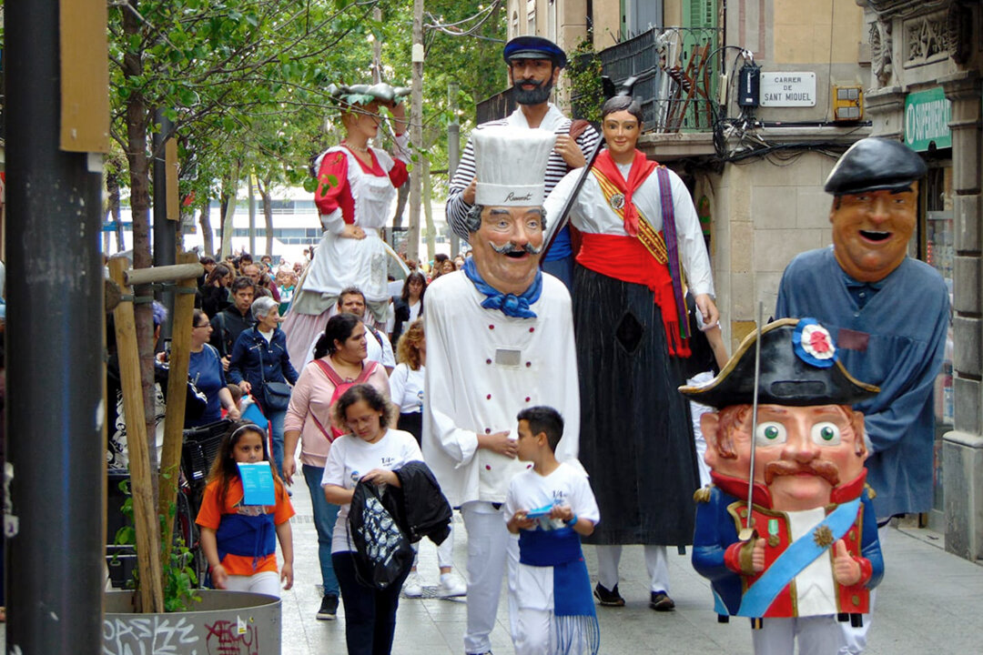 A festive street scene in Barceloneta during Festa Major, with decorated streets and a procession featuring traditional giants and local residents.