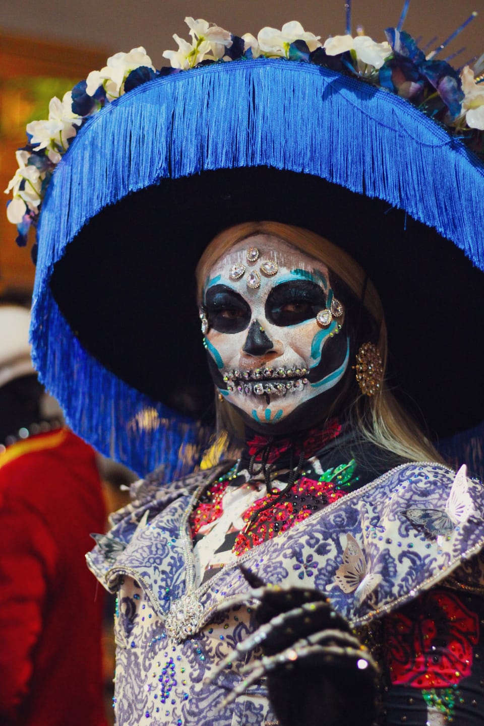 A vibrant procession of elaborately dressed Catrinas walks along the waterfront at Port Vell in Barcelona.