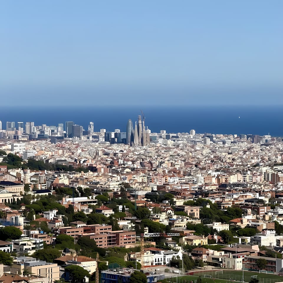 A misty autumn morning in Horta, Barcelona, with trees showing early signs of seasonal change and cool air settling over the city.