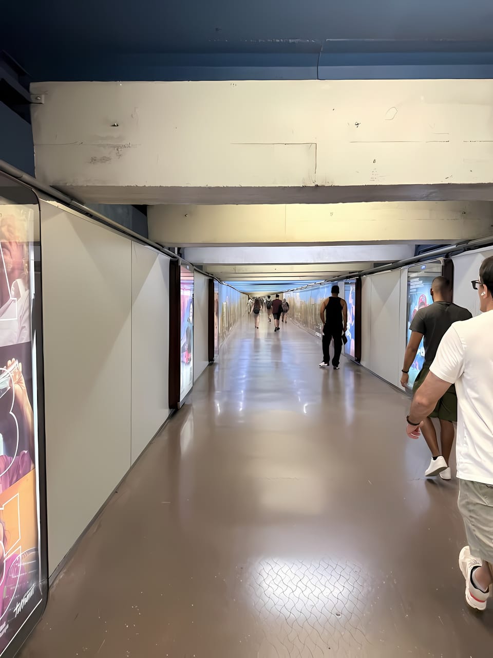 Interior view of the Plaça Catalunya metro interchange hall in Barcelona, showing a tiled corridor with lighting fixtures and signs for lines L1 and L3.