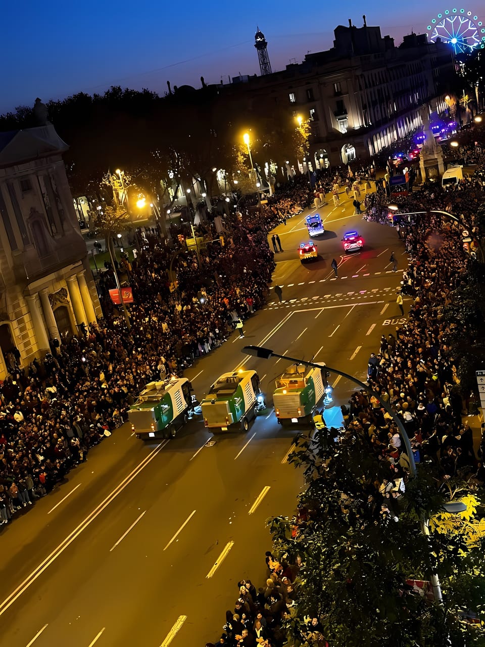Crowd gathers along the parade route at the 2026 Three Kings Parade in Barcelona, with floats and performers visible under evening lights.