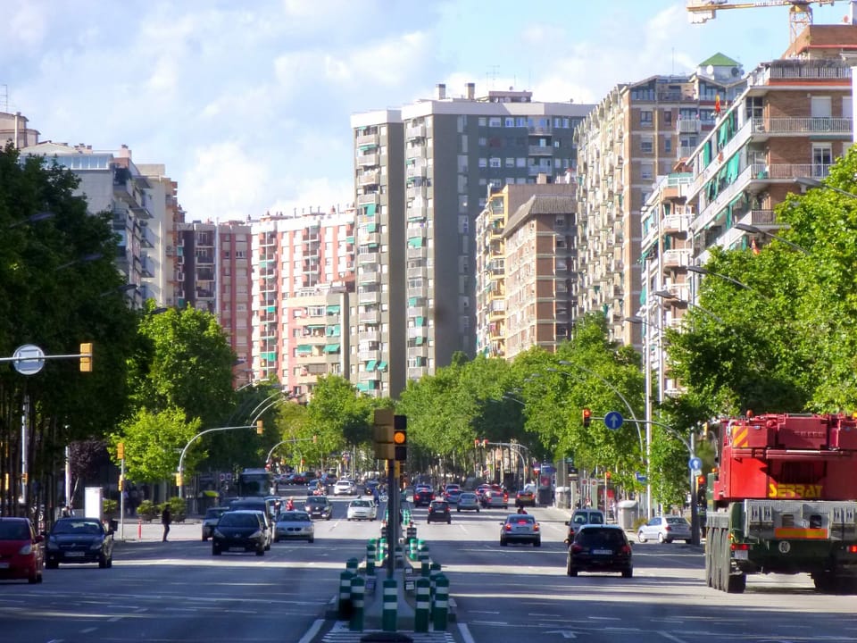 A busy bus stop on Avenida Meridiana near Sagrera, with passengers waiting under a small shelter alongside traffic.