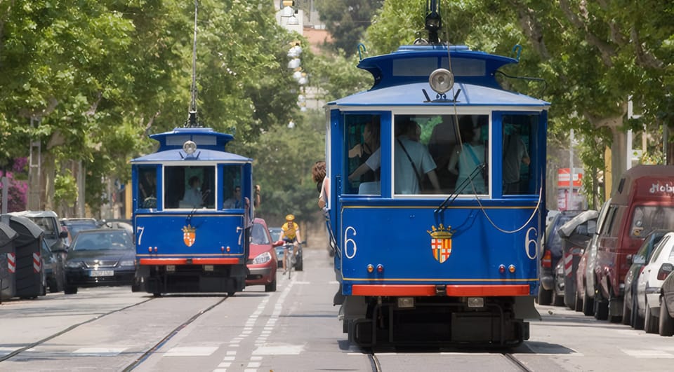 Historic Tramvia Blau parked under plane trees on Avinguda del Tibidabo in Barcelona, with passengers boarding near Plaça Kennedy.
