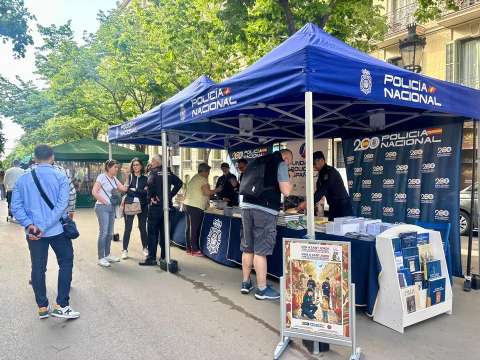 A street scene in Barcelona during Sant Jordi, with people browsing book and rose stalls, possibly on Rambla de Catalunya.