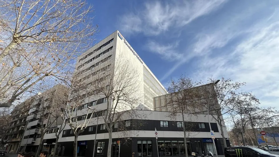 Exterior view of the Travelodge Poblenou hotel in Barcelona, a modern building with a blue and white facade under a clear sky