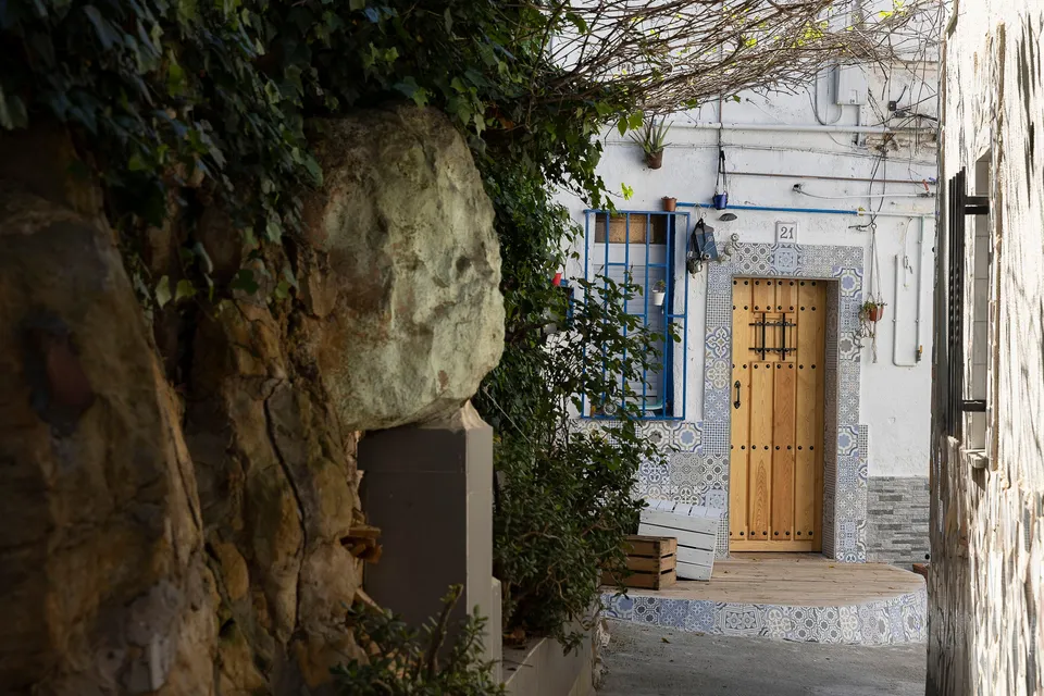 A stone wall with the number 36 in blue tiles, symbolising a demolished house in Barcelona's Turó de la Guatlla neighbourhood