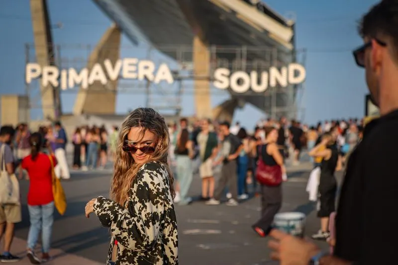 A large crowd of people enjoying a music festival at Parc del Fòrum in Barcelona, with a stage and lights in the background.