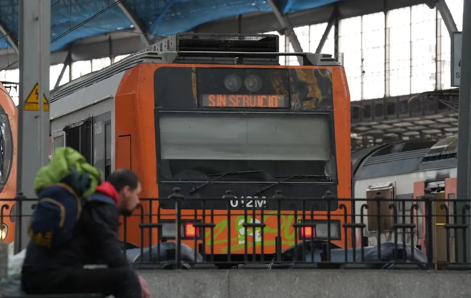 A Rodalies train arriving at a station platform in Barcelona, with passengers waiting to board.